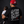 A man wearing a black t-shirt with a large white script graphic on the back and a red baseball cap sits holding a baby against a dark studio background. The t-shirt features the text 'Go To Work Get Money Home Come Home' and 'PROUD FATHER APPAREL'.